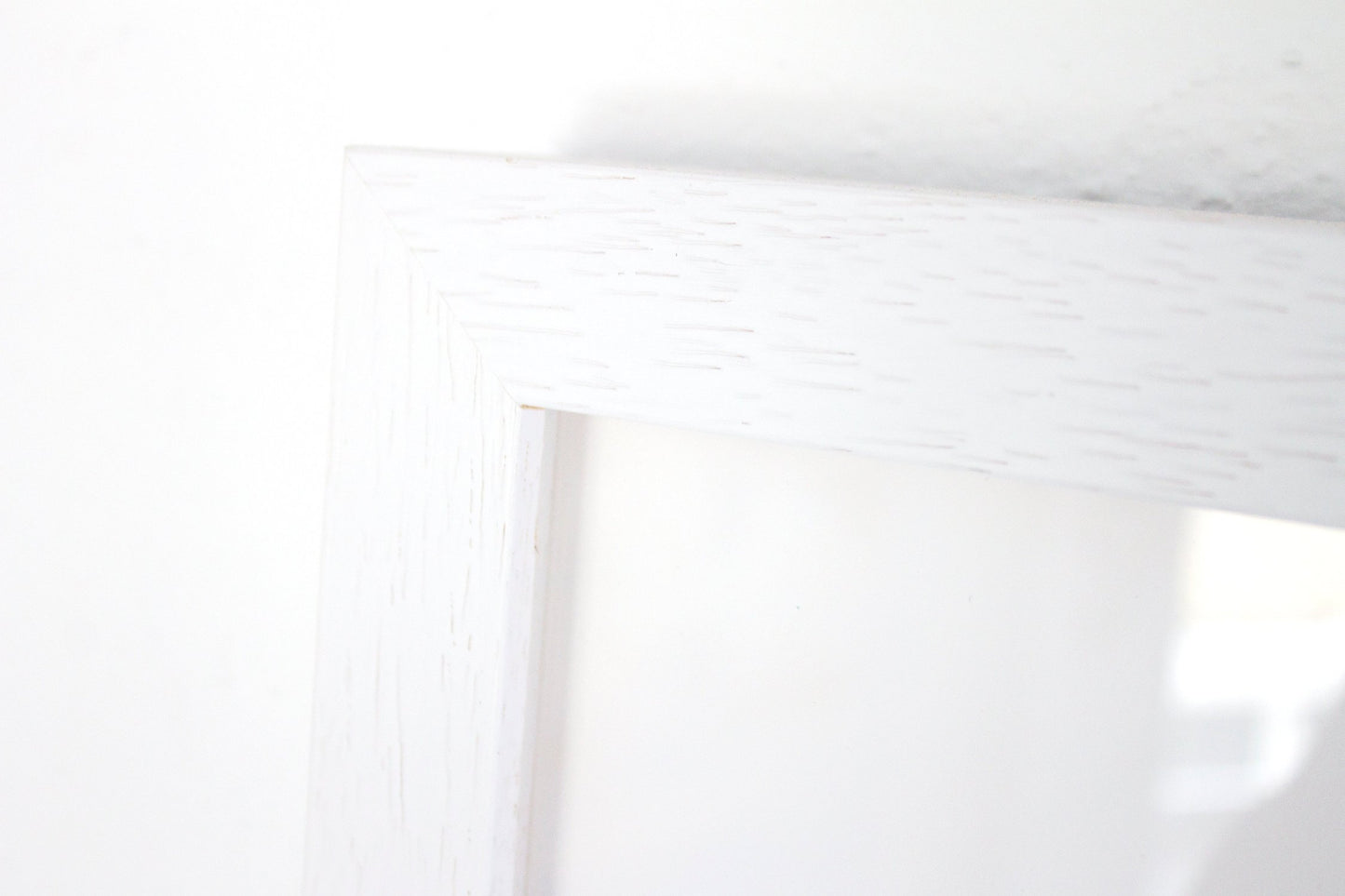 Close up detail of a white box frame with wood grain detail.