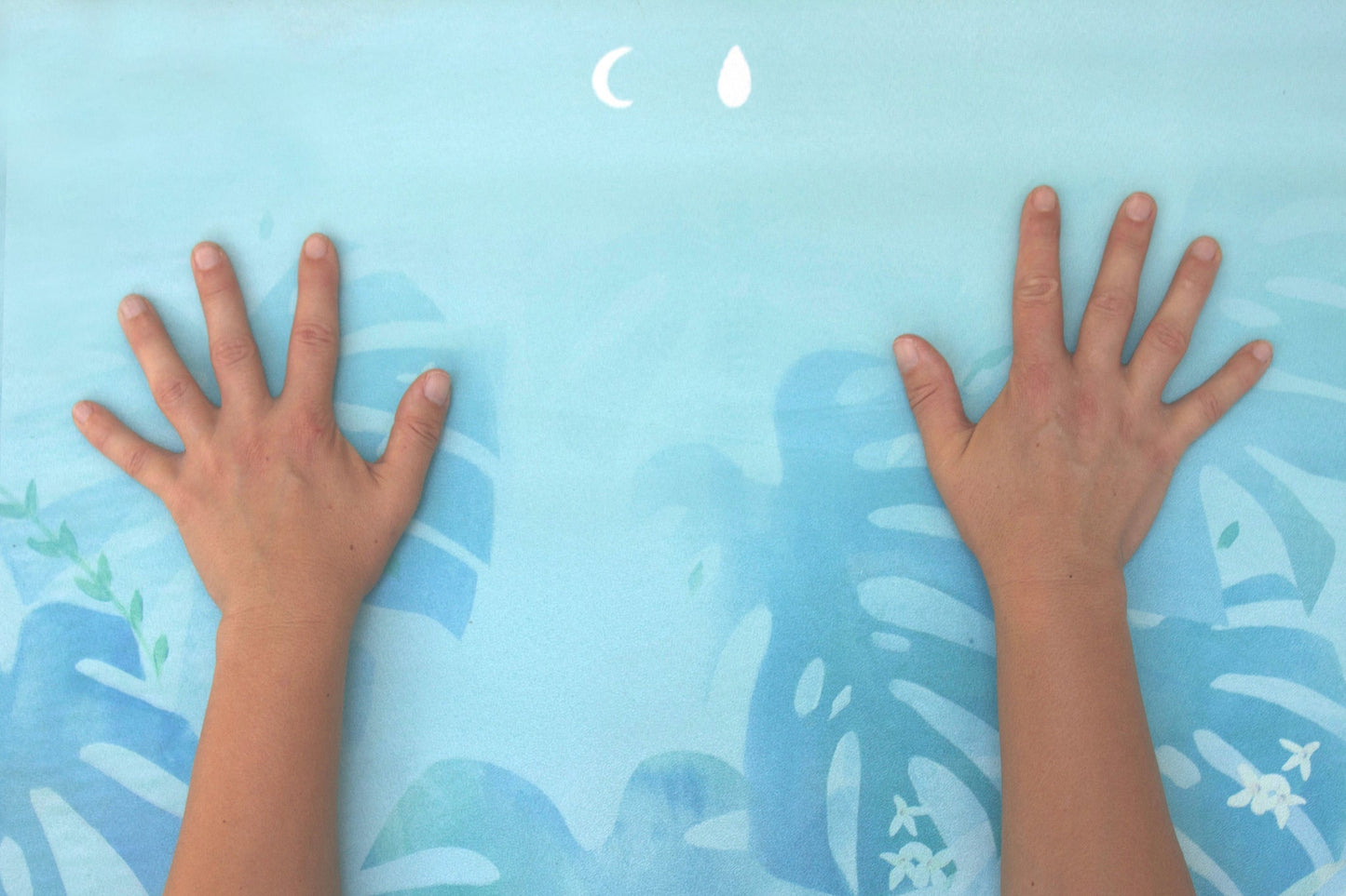 Two hands placed on a blue mat with nature-themed design