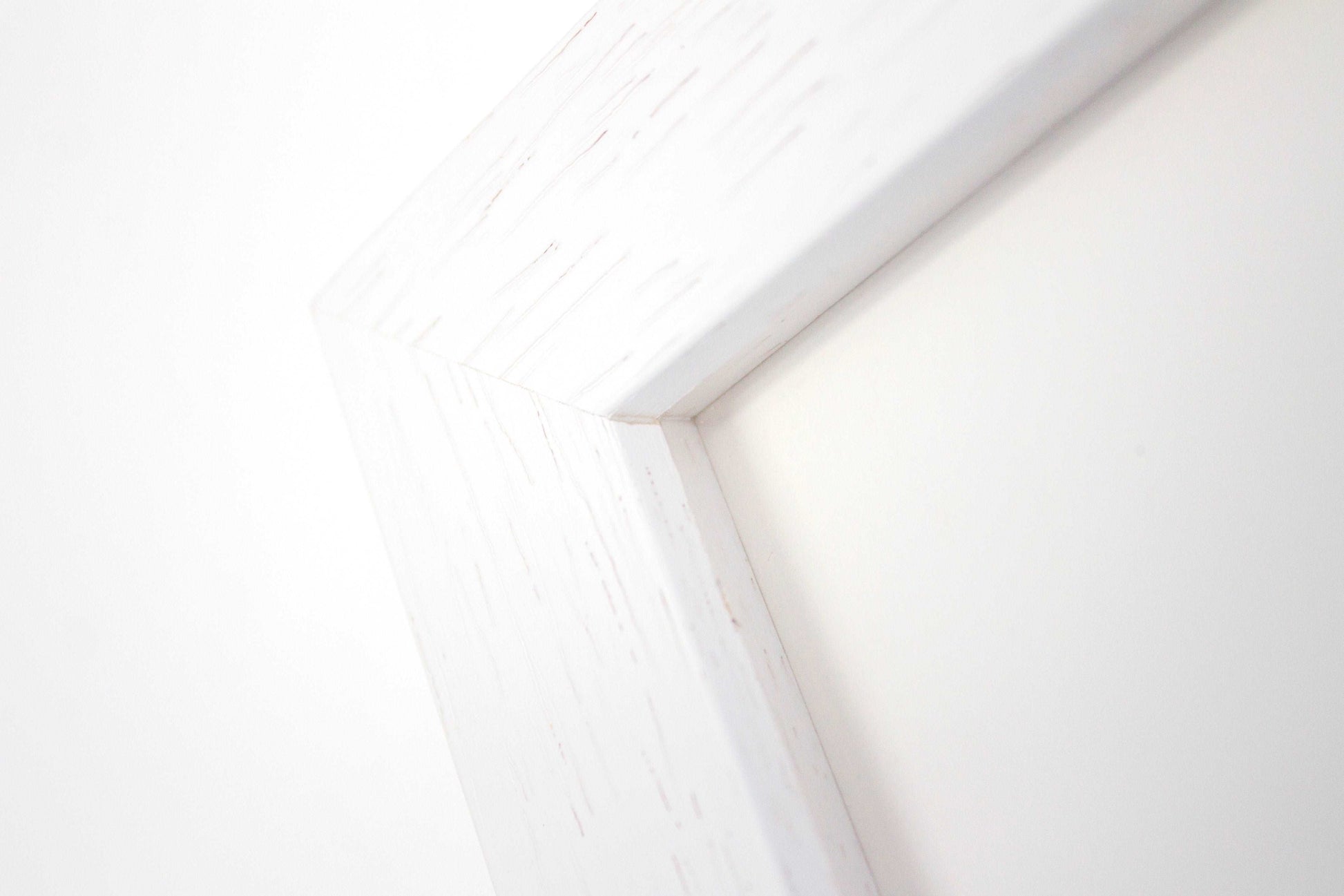 Frame detail of a white box frame with wood grain.