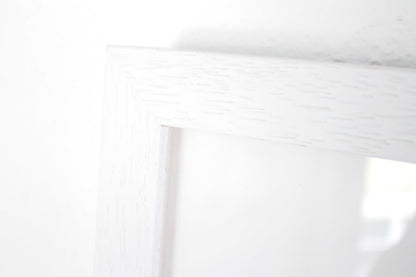 Close up detail of a white frame against a white wall.
