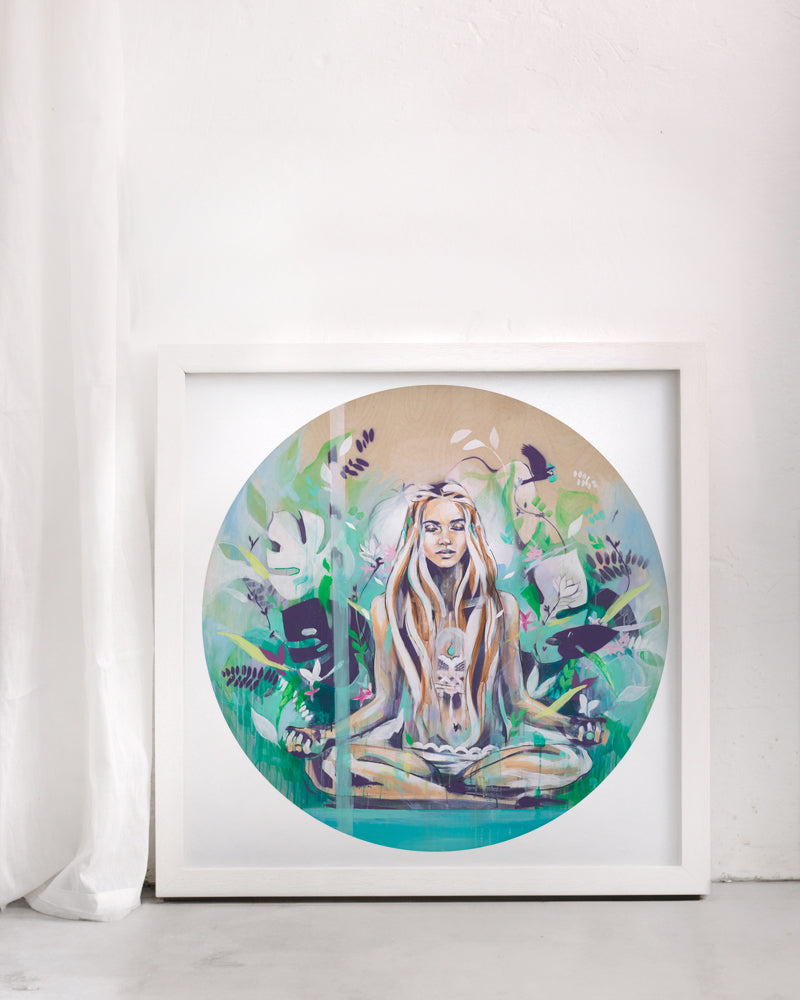 Yoga meditation print of a woman surrounded by green and turquoise. In a white frame in a white room.