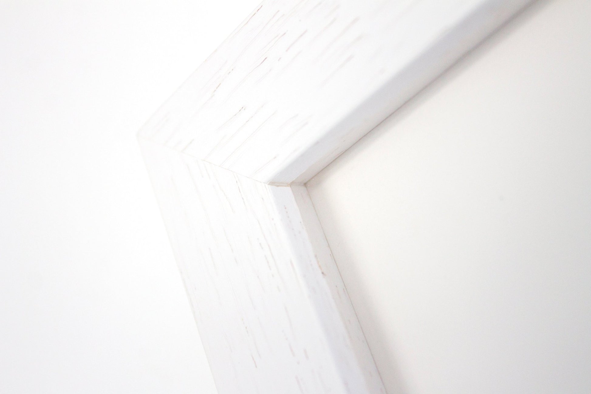 Close up detail of a white box frame with woodgrain.