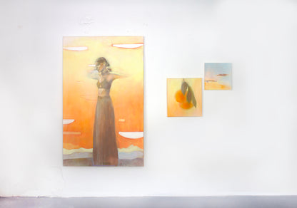 Gallery wall with warm abstract paintings including figure art, orange still life, and sunset landscape wall art in golden tones.