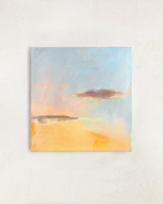Sunset wall art with warm golden tones and soft blue sky, abstract landscape painting displayed in a neutral interior.