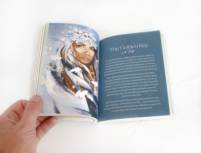 Open guidebook from the Golden Keys of Gaia oracle deck showing elemental wisdom text and illustrated artwork